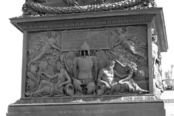 Барельеф: две фигуры держат доску с надписью «Александру I благодарная Россия», под ними доспехи витязей, по сторонам от доспехов - фигуры, олицетворяющие реки Вислу и Неман